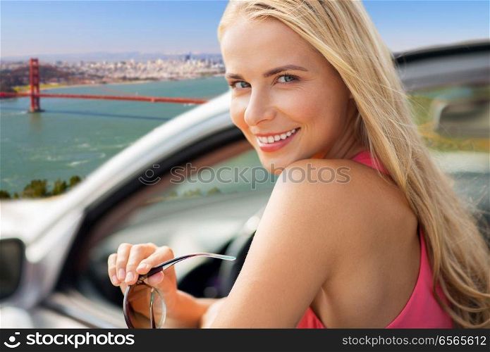 travel, road trip and people concept - close up of happy young woman in convertible car over golden gate bridge in san francisco bay background. woman in convertible car over golden gate bridge