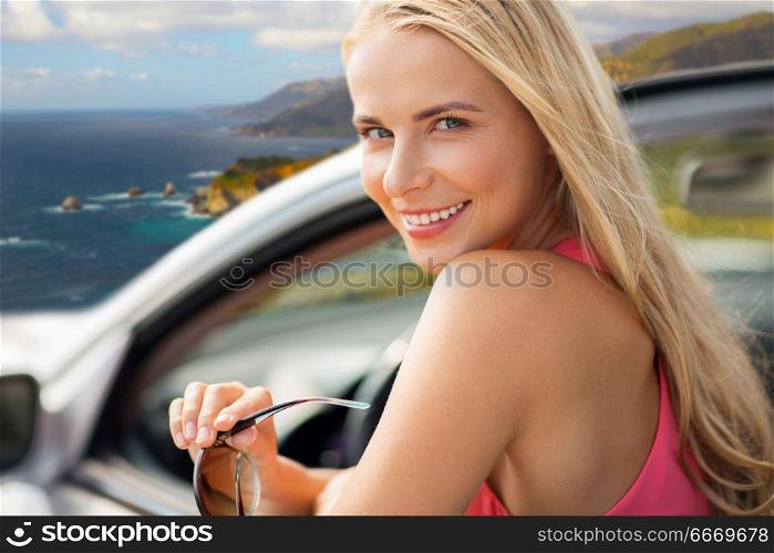 travel, road trip and people concept - close up of happy young woman in convertible car over big sur coast of california background. happy woman in convertible car over big sur coast. happy woman in convertible car over big sur coast