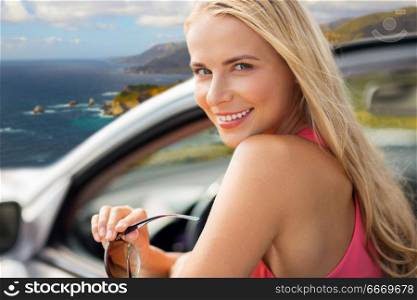 travel, road trip and people concept - close up of happy young woman in convertible car over big sur coast of california background. happy woman in convertible car over big sur coast. happy woman in convertible car over big sur coast