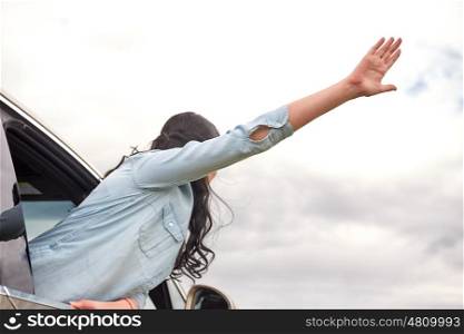 travel, road trip and people concept - happy woman waving hand leaning out of car window