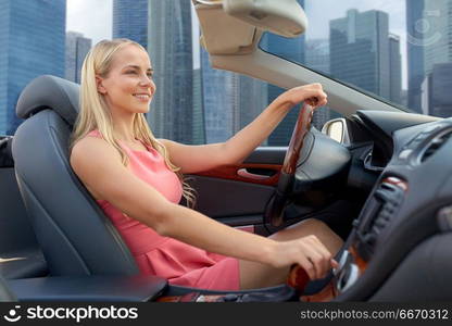 travel, road trip and people concept - happy young woman driving convertible car over singapore city skyscrapers background. woman driving convertible car over singapore city. woman driving convertible car over singapore city