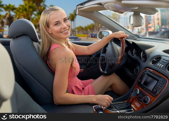 travel, road trip and people concept - happy young woman driving convertible car over venice beach background in california. woman driving convertible car over venice beach