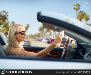 travel, road trip and people concept - happy young woman in convertible car taking selfie by smartphone over venice beach background in california. woman in convertible car taking selfie over beach. woman in convertible car taking selfie over beach
