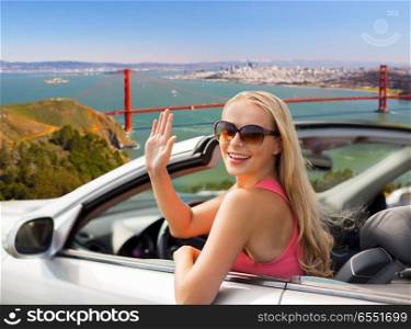 travel, road trip and people concept - happy young woman in convertible car waving hand over golden gate bridge in san francisco bay background. happy young woman in convertible car waving hand. happy young woman in convertible car waving hand