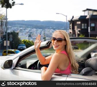 travel, road trip and people concept - happy young woman in convertible car waving hand over san francisco city background. happy young woman in convertible car waving hand