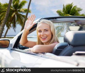 travel, road trip and people concept - happy young woman in convertible car waving hand over tropical beach background in french polynesia. woman in convertible car waving hand over beach. woman in convertible car waving hand over beach