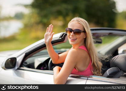 travel, road trip and people concept - happy young woman in convertible car waving hand. happy young woman in convertible car waving hand