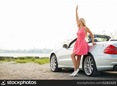 travel, road trip and people concept - happy young woman in convertible car waving hand. happy young woman in convertible car waving hand