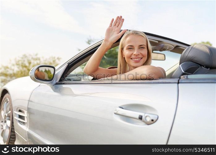 travel, road trip and people concept - happy young woman in convertible car waving hand. happy young woman in convertible car waving hand