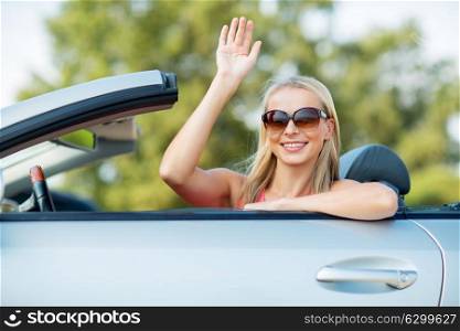 travel, road trip and people concept - happy young woman in convertible car waving hand. happy young woman in convertible car waving hand
