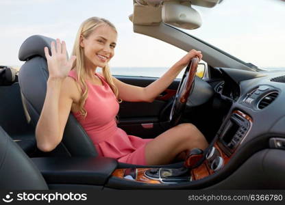 travel, road trip and people concept - happy young woman in convertible car waving hand. happy young woman in convertible car waving hand