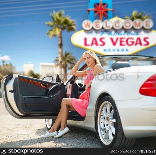 travel, road trip and people concept - happy young woman posing in convertible car over welcome to fabulous las vegas sign background. woman in convertible car over las vegas sign. woman in convertible car over las vegas sign