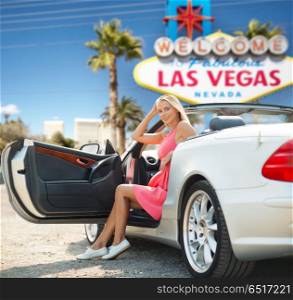travel, road trip and people concept - happy young woman posing in convertible car over welcome to fabulous las vegas sign background. woman in convertible car over las vegas sign. woman in convertible car over las vegas sign