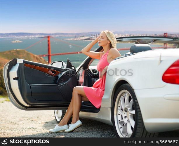 travel, road trip and people concept - happy young woman posing in convertible car over golden gate bridge in san francisco bay background. woman in convertible car over golden gate bridge. woman in convertible car over golden gate bridge