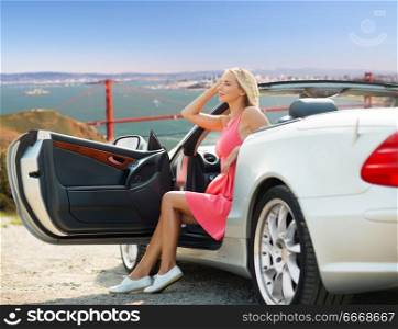 travel, road trip and people concept - happy young woman posing in convertible car over golden gate bridge in san francisco bay background. woman in convertible car over golden gate bridge. woman in convertible car over golden gate bridge