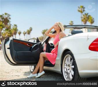 travel, road trip and people concept - happy young woman posing in convertible car over venice beach background in california. woman posing in convertible car over venice beach. woman posing in convertible car over venice beach