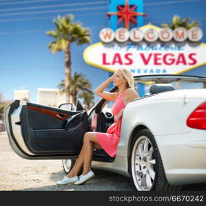 travel, road trip and people concept - happy young woman posing in convertible car over welcome to fabulous las vegas sign background. woman in convertible car over las vegas sign. woman in convertible car over las vegas sign