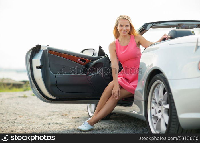 travel, road trip and people concept - happy young woman posing in convertible car. happy young woman porisng in convertible car