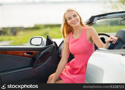 travel, road trip and people concept - happy young woman posing in convertible car. happy young woman porisng in convertible car