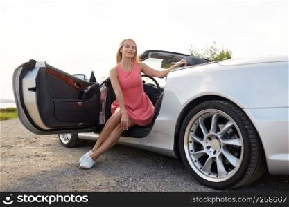 travel, road trip and people concept - happy young woman posing in convertible car at seaside. happy young woman posing in convertible car