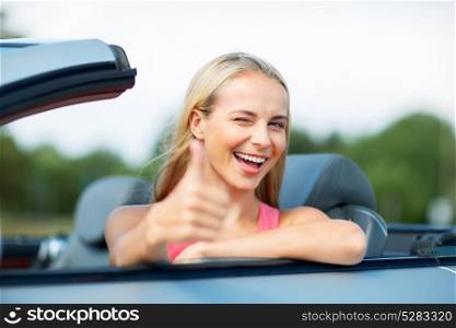 travel, road trip and people concept - happy young woman showing thumbs up in convertible car. happy young woman in convertible car thumbs up