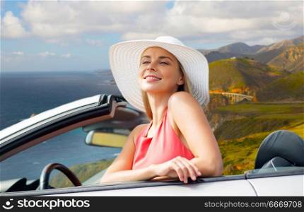 travel, road trip and people concept - happy young woman wearing sun hat in convertible car over bixby creek bridge on big sur coast of california background. woman in hat in convertible car on big sur coast. woman in hat in convertible car on big sur coast