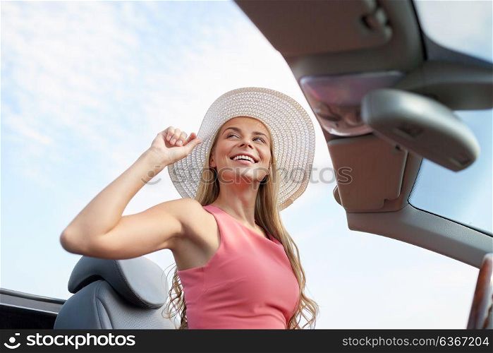 travel, road trip and people concept - happy young woman wearing sun hat in convertible car. happy young woman in convertible car