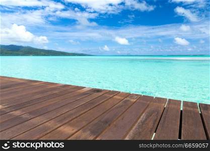 travel, seascape and nature concept - wooden pier on tropical beach in french polynesia. wooden pier on tropical beach in french polynesia