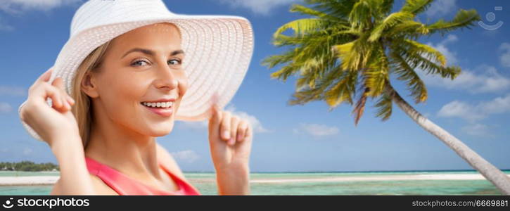 travel, summer holidays and tourism concept - portrait of beautiful smiling woman in sun hat over exotic tropical beach with palm trees background. portrait of smiling woman in sun hat over beach. portrait of smiling woman in sun hat over beach