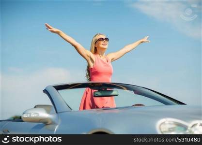 travel, summer holidays, road trip and people concept - happy young woman wearing sunglasses in convertible car enjoying sun. happy young woman in convertible car