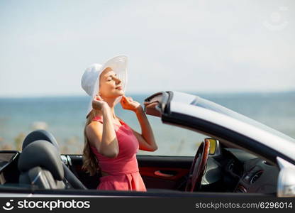 travel, summer holidays, road trip and people concept - happy young woman wearing hat in convertible car enjoying sun. happy young woman in convertible car