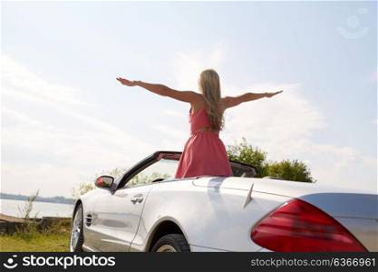 travel, summer holidays, road trip and people concept - happy young woman in convertible car enjoying sun at seaside. happy young woman in convertible car at seaside