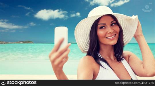 travel, summer, technology and people concept - sexy young woman taking selfie with smartphone over tropical beach background