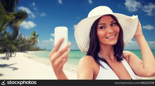 travel, summer, technology and people concept - sexy young woman taking selfie with smartphone over tropical beach with palms background