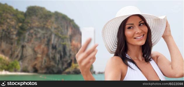 travel, summer, technology and people concept - sexy young woman taking selfie with smartphone over rock on bali beach background