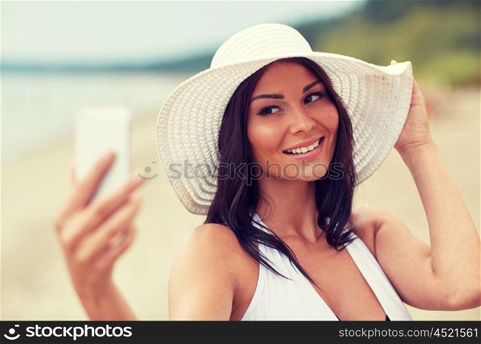 travel, summer, technology and people concept - sexy young woman taking selfie with smartphone on beach