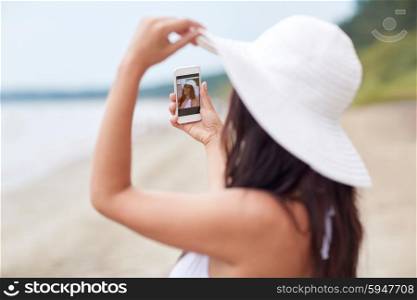 travel, summer, technology and people concept - sexy young woman taking selfie with smartphone on beach
