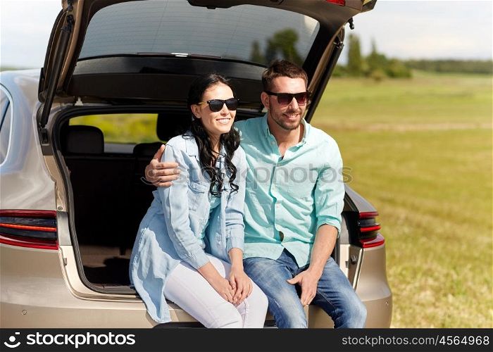 travel, summer vacation, road trip, leisure and people concept - happy couple hugging at open trunk of hatchback car outdoors