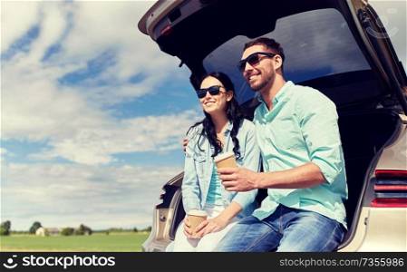 travel, summer vacation, road trip, leisure and people concept - happy couple drinking coffee from disposable cups sitting on trunk of hatchback car outdoors. happy couple with coffee at hatchback car trunk