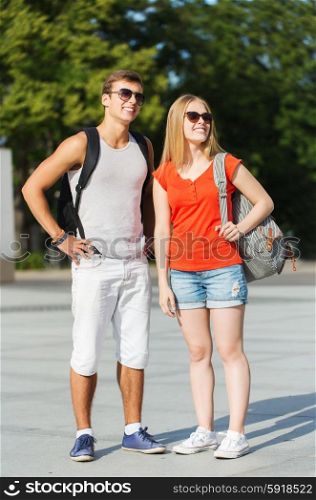 travel, summer vacation, tourism and friendship concept - smiling couple with backpacks in city