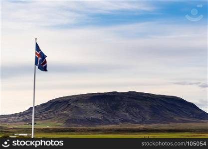 travel to Iceland - icelandic flag and view of hill near Kerid Lake in september evening