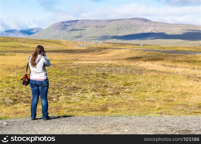 travel to Iceland - the tourist photographs a landscape with Thingvallavegur country road in Iceland in sunny september day