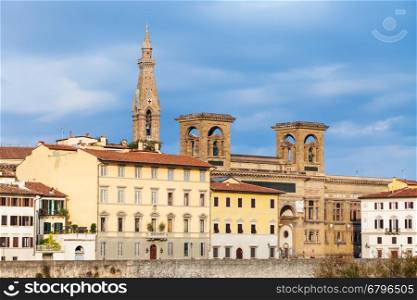 travel to Italy - houses on quay of Arno River and towers of Basilica di Santa Croce (Basilica of the Holy Cross) illuminated by sun in Florence city