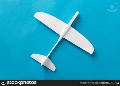 travel, tourism and air transportation concept - white toy plane model on blue background. white toy plane model on blue background