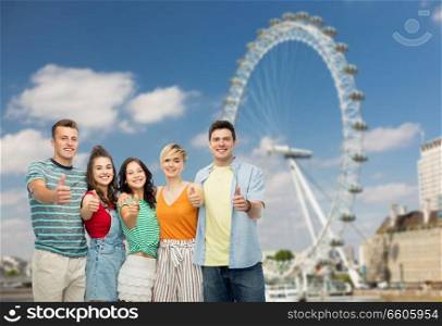 travel, tourism and entertainment concept - group of happy smiling friends showing thumbs up over ferry wheel in london background. friends showing thumbs up over ferry wheel