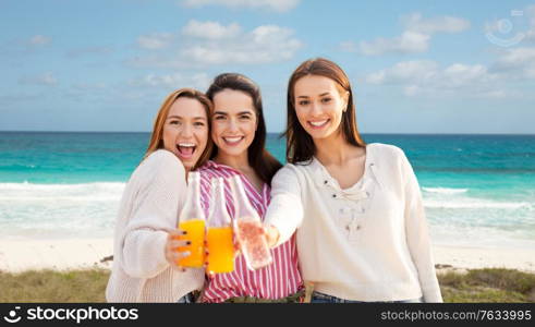 travel, tourism and friendship concept - group of happy young women or female friends toasting non alcoholic drinks over tropical beach background in french polynesia. young women toasting non alcoholic drinks on beach