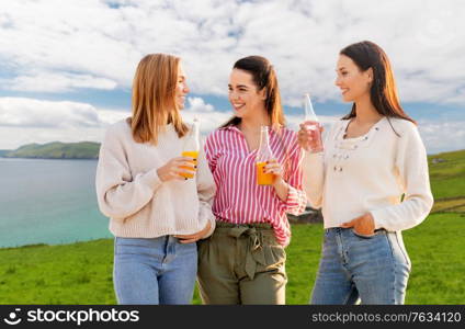 travel, tourism and friendship concept - group of happy young women or female friends with non alcoholic drinks talking over ireland on background. women with non alcoholic drinks talking in ireland