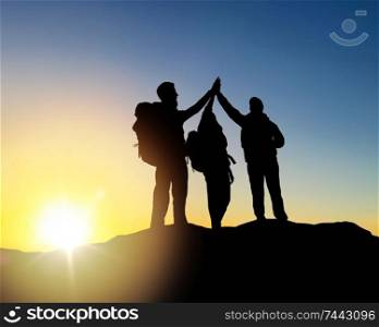 travel, tourism and hike concept - group of travelers with backpacks making high five on mountain top over sunrise background. travelers making high five over sunrise