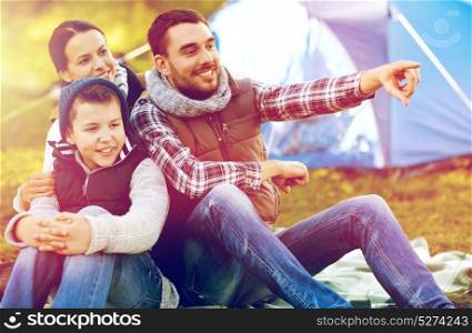 travel, tourism and hike concept - happy family over tent at camp site pointing finger to something. happy family with tent at camp site