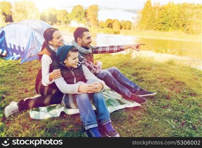 travel, tourism and hike concept - happy family over tent at camp site pointing finger to something. happy family with tent at camp site